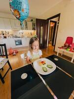 Podgorica, Montenegro - 14 august 2023. Little birthday girl sits in front of a plate of rabbit-shaped rice at the table photo