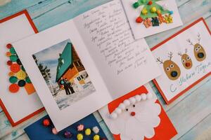 Colorful New Year cards with wishes and decorations lie on a wooden table photo