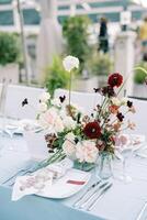 Plate with an invitation stands on a set table near a bouquet photo