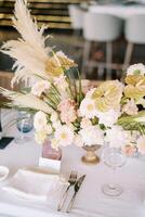 Large bouquet of flowers stands on the festive table near the name card in front of the plate photo