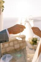 novia y novio tintinar lentes de champán en contra el fondo de un soleado cielo. recortado sin rostro foto