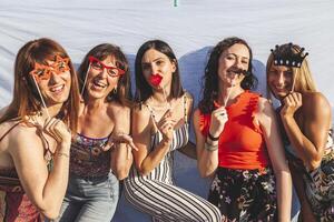 group of female friends having fun with party accessories on the roofs photo