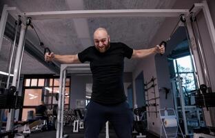 athlete while doing heavy exercises at the cables photo