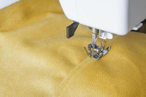 moderno de coser máquina con amarillo terciopelos tela cerca arriba foto