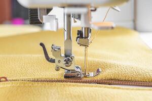 Modern sewing machine with yellow velours fabric close up photo