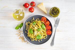 Traditional italian spaghetti pasta pesto and ingredients in gray plate on white wooden background photo