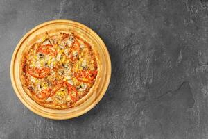 Italian pizza with melted mozzarella cheese mushrooms, corn and tomato on gray stone background. photo