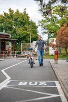 Prague, Czech republic - October 10, 2023. Happy young father teaches child daughter to ride public bike on one of traffic playground in Prague, Czech republic. High quality photo