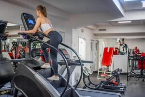 Woman walking on climbing machine in a fitness club, gym, cardio workout. . High quality photo