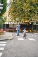 padre enseña niño hija a paseo público bicicleta en uno de tráfico patio de recreo en praga, checo república, Europa. alto calidad foto