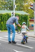 Happy family father teaches child daughter to ride public bike on traffic playground of Prague, Czech republic. High quality photo