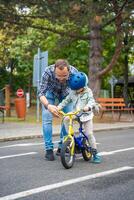 Young happy father teaches child daughter to ride public bike on one of traffic playground of Prague, Czech republic. High quality photo