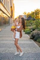 Mom and her little daughter playing on city street at sunset lights in summer. High quality photo