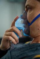 Unhealthy man wearing nebulizer mask in home. Health, medical equipment and people concept. High quality photo