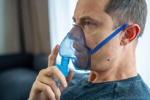 insalubre hombre vistiendo nebulizador máscara en hogar. salud, médico equipo y personas concepto. alto calidad foto