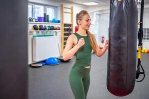 Young woman stands next to a black boxing pear to let off steam in gym. High quality photo