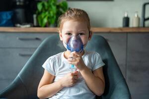 linda pequeño niña son sentado y participación un nebulizador máscara propensión en contra el rostro, vías respiratorias tratamiento concepto. alto calidad foto