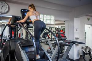 Woman walking on climbing machine in a fitness club, gym, cardio workout. . High quality photo