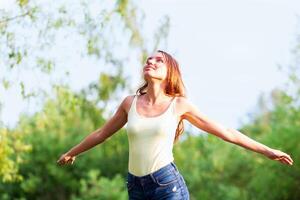 Pretty girl breathing clear and fresh air in summer park photo