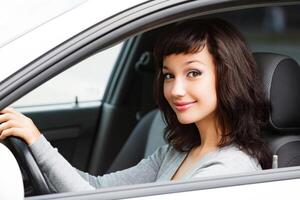 bonito mujer conductor sonriente a usted desde el blanco coche foto