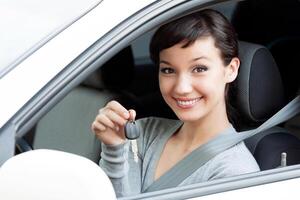 Happy owner of a new car is showing the car key. Pretty girl driver photo