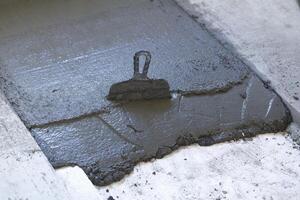 trowel in a layer of fresh concrete on the floor photo