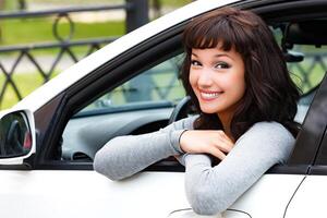 bonito mujer conductor sonriente a usted desde el blanco coche foto