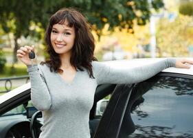 Happy female driver showing car key photo