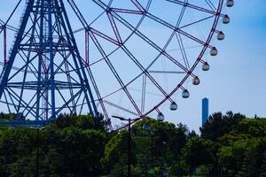 A ferris wheel at the park behind the blue sky telephoto shot photo