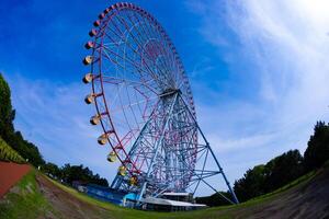 A ferris wheel at the park behind the blue sky fish-eye shot photo