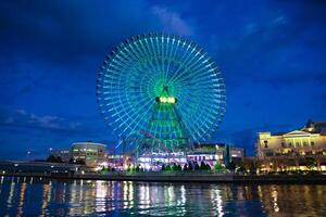 un noche iluminado ferris rueda en Yokohama amplio Disparo foto
