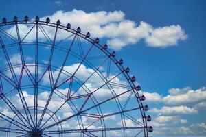 A ferris wheel at the park behind the blue sky telephoto shot photo