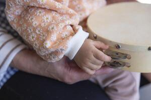 Child's hands with tambourine in the living room closeup photo