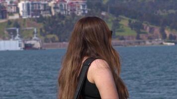 Frau sieht aus beim das Stadt Aussicht von das Fähre Deck beim Meer Filmaufnahme. video