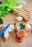 fried toast with salmon, cream cheese, salad, on a wooden table photo