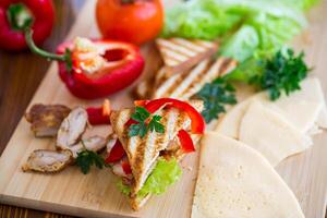 fried toast with chicken, salad, greens on a wooden table photo