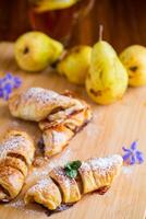 Sweet pastries, puff pastries with pears, on a wooden table photo