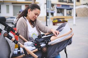 Young pretty woman enjoy happy maternity leave time with her newborn child sleeping in the baby carriage, baby pram photo