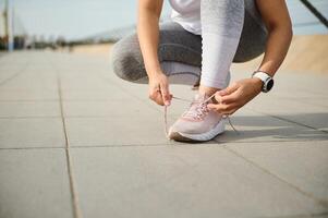 de cerca de un mujer atleta corredor persona que practica jogging en gris polainas, atadura cordones en su rosado zapatillas, corriendo Zapatos foto