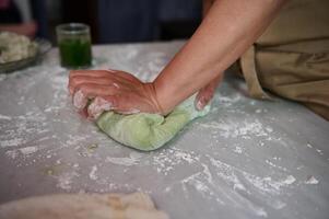 Close-up hands of a housewife kneading dough on the floured kitchen table, making dumplings for dinner photo