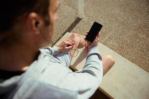 Overhead view of young athlete using mobile phone with blank black mockup screen, copy advertising space for mobile app photo