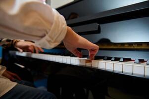 músico pianista pone dedos en piano llaves, jugando piano, disfrutando actuación de clásico melodía durante música lección foto