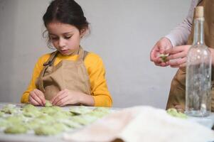 Children learning making dumplings during a cooking class. Preparing homemade varennyky according to traditional Ukrainian recipe photo