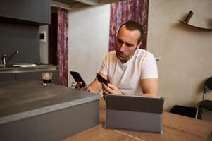 Young man holding credit card, using smartphone, paying bills, receiving or making payment via mobile internet banking photo