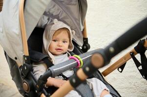 Beautiful blue eyed baby boy 6-11 months old, smiling at camera, sitting in his baby pram stroller carriage pushchair photo