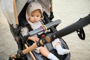 A cute baby boy in the baby pram, baby stroller, pushchair during a family walk outdoors photo