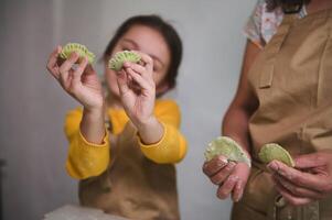 detalles en esculpido empanadillas en niño muchachas manos. niños aprendizaje Cocinando durante culinario clase maestra. madre y hija Cocinando juntos hecho en casa ucranio varennyky para familia cena foto