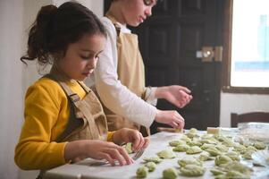 Boy and girl learning culinary at cooking class, making homemade dumplings with mashed potato filling photo