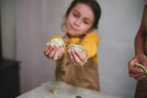 detalles en dos moldeado hecho en casa empanadillas en niño muchachas manos. niños aprendizaje Cocinando durante culinario clase maestra foto