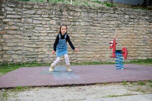 Sporty child girl plays hopscotch, takes turns jumping over squares marked on ground. Kids and active healthy lifestyle photo